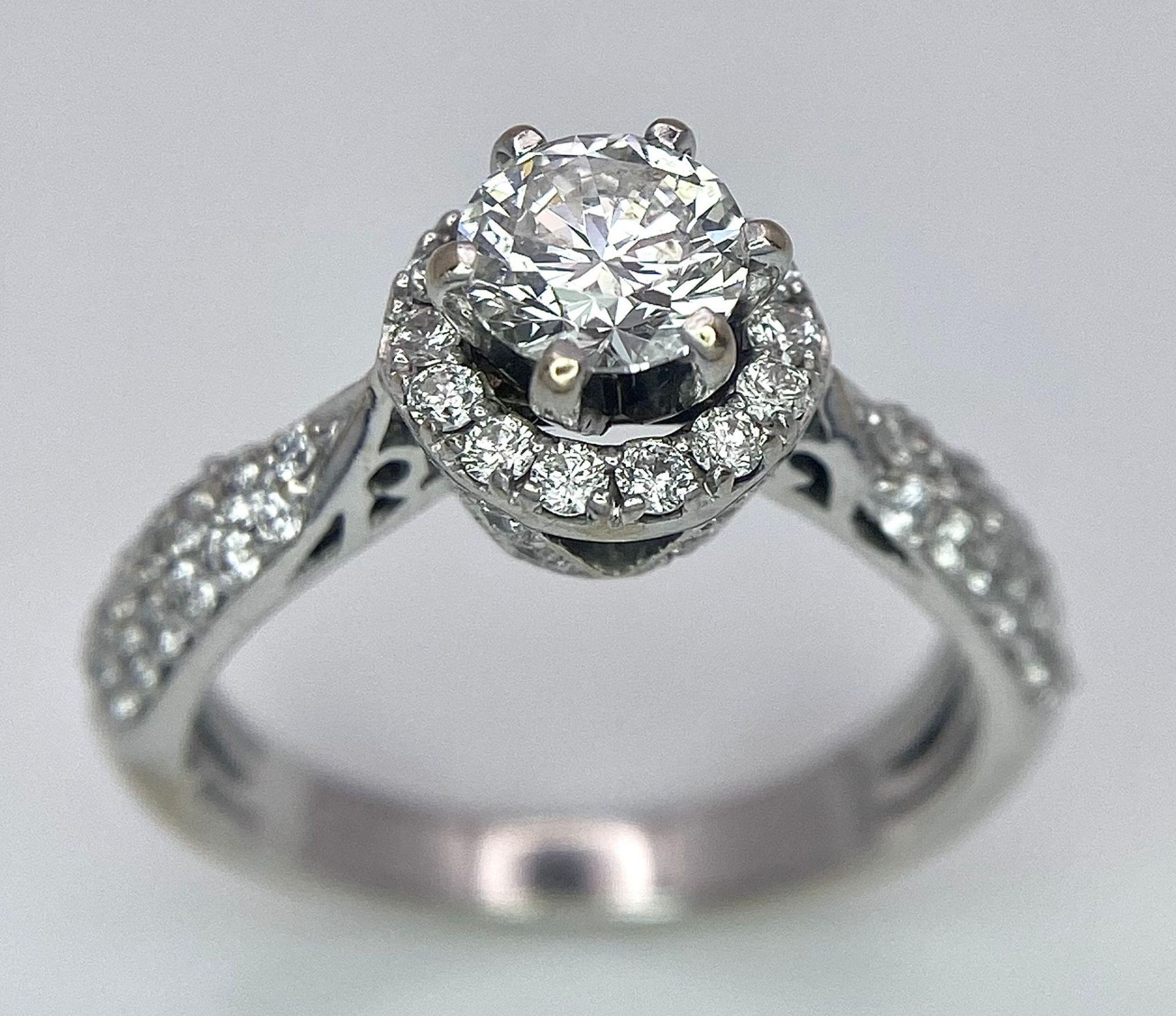 An 18K White Gold Diamond Ring. Central 0.75ct brilliant round cut diamond with a diamond halo and