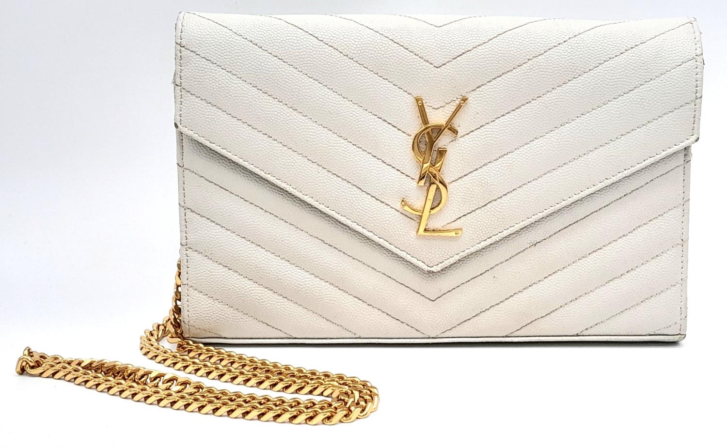 A YSL Ivory Cassandre Wallet Bag. Leather exterior with gold-toned hardware, the iconic YSL logo,