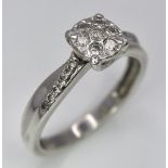 A 9K White Gold Diamond Cluster Ring. Seven small diamonds on a circular base with diamonds on