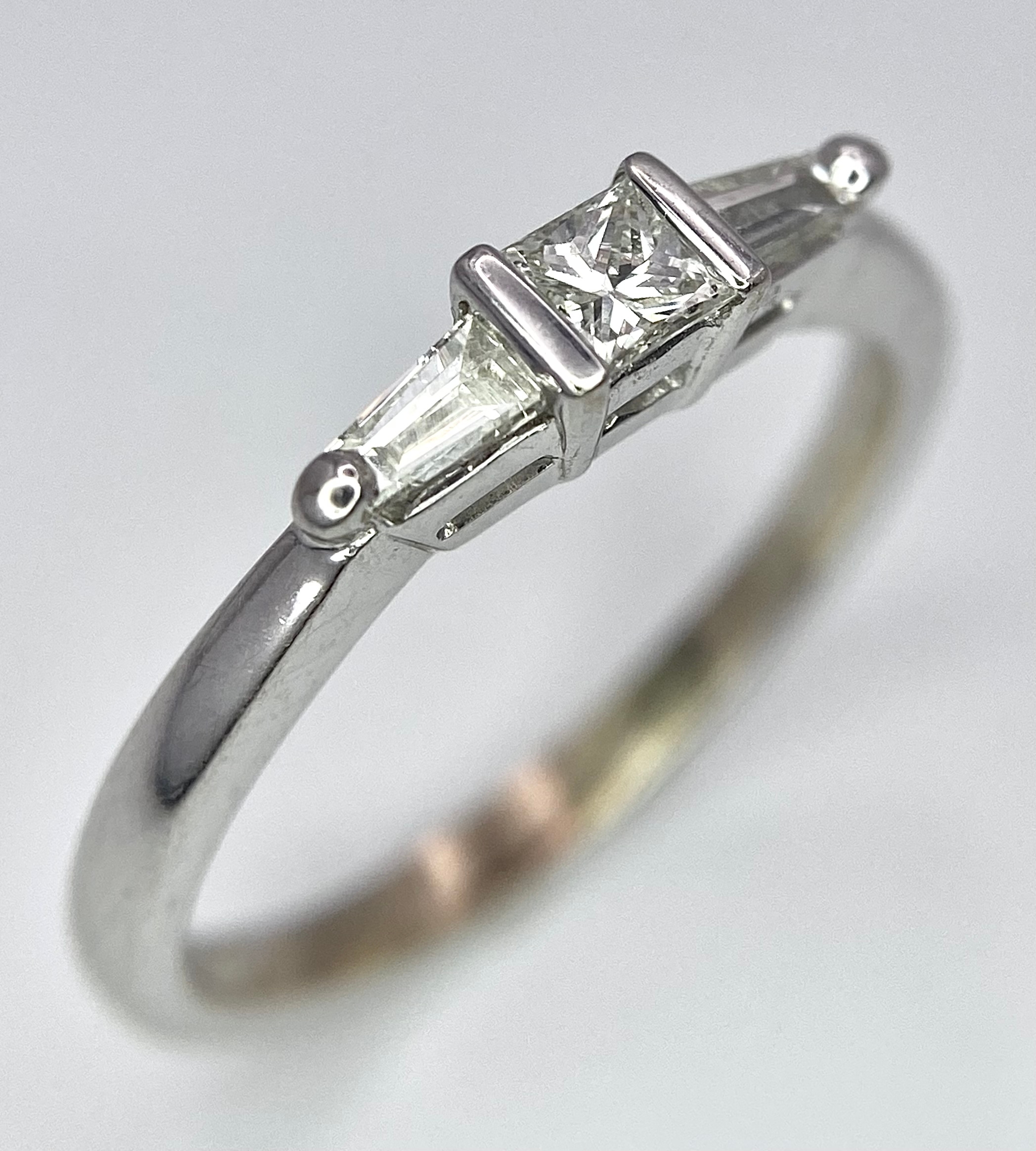AN 18K WHITE GOLD, DIAMOND 3 STONE RING - PRINCESS CUT CENTRE WITH A TAPPERED BAGUETTE DIAMOND