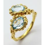 A very feminine sterling silver and yellow gold ring with two oval cut aquamarines symbolising