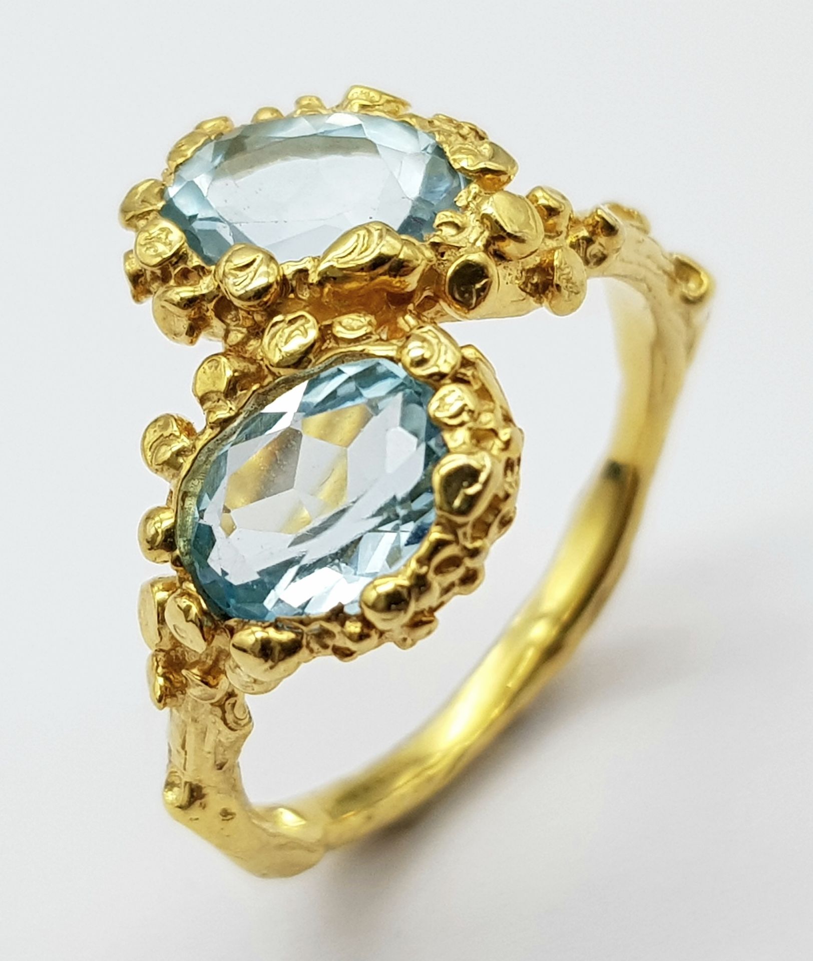 A very feminine sterling silver and yellow gold ring with two oval cut aquamarines symbolising