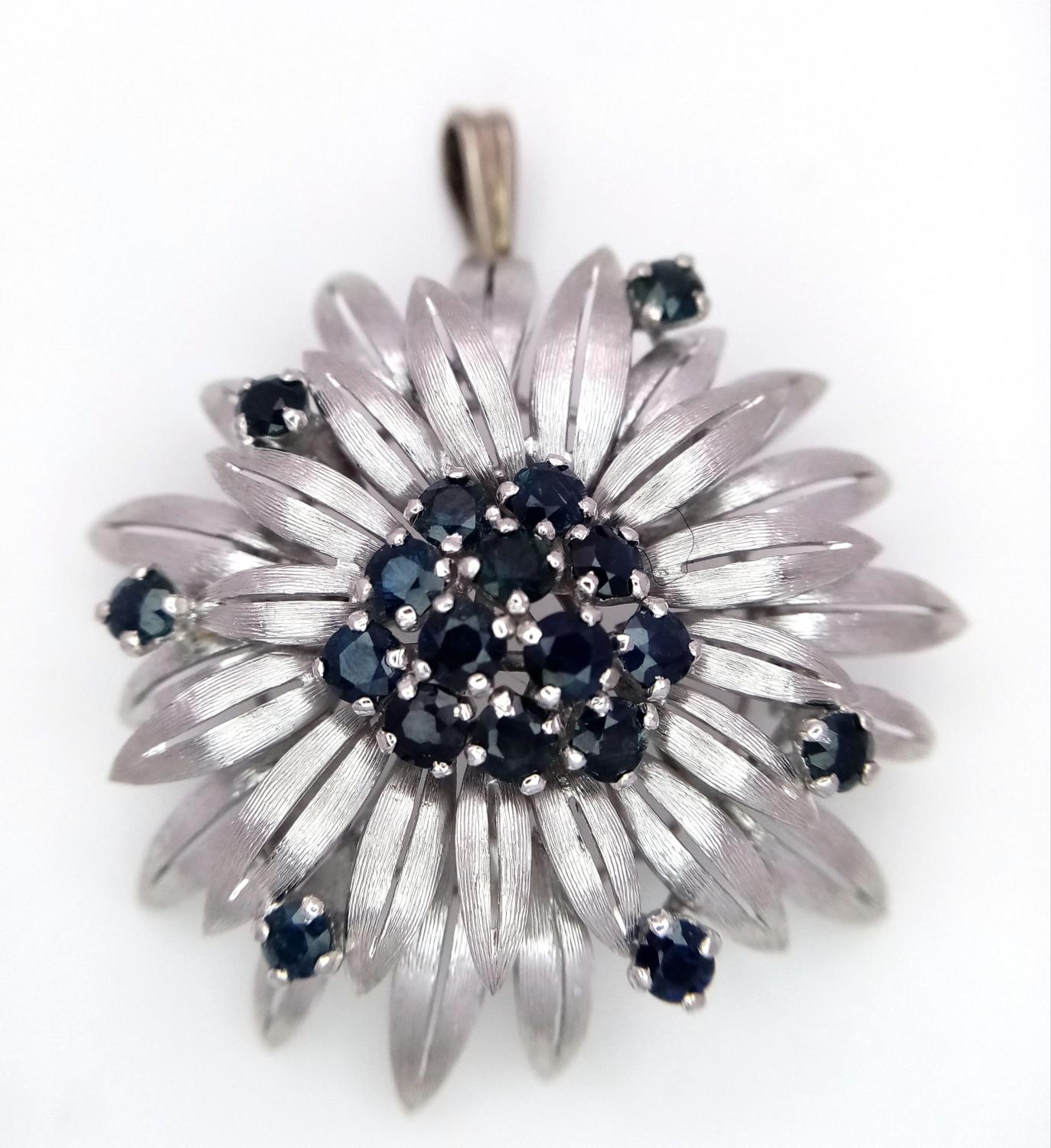 A 14ct white gold (tested as) sapphire flower brooch that has a bail that can be worn as a