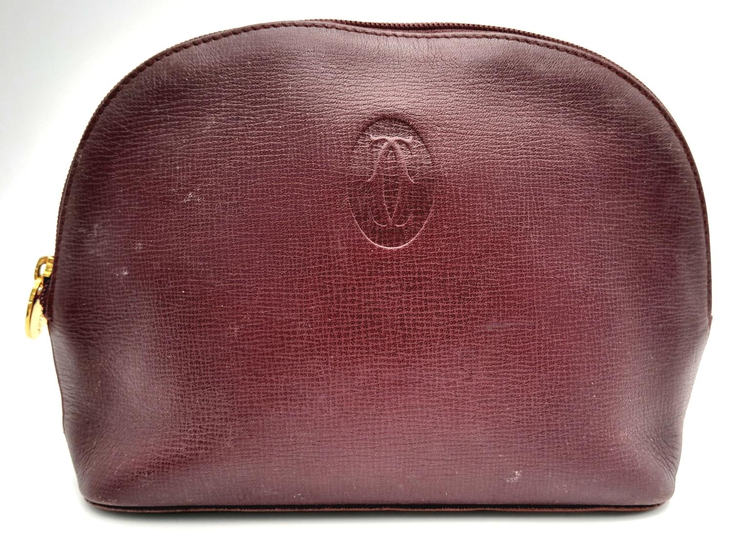 A Vintage Cartier Burgundy Pouch. Leather exterior with zip top closure. Burgundy canvas interior.