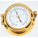 A Nautical, polished brass, KELVIN HUGHES barometer, having the shape of a ship-cabin’s porthole,