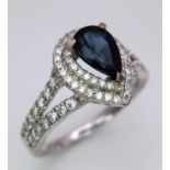 An 18K White Gold Sapphire and Diamond Ring. Teardrop sapphire with a 0.50ctw diamond surround. Size