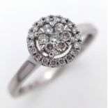 A 9K White Gold Diamond Cluster Ring. A circle of round cut diamonds with a halo of smaller round