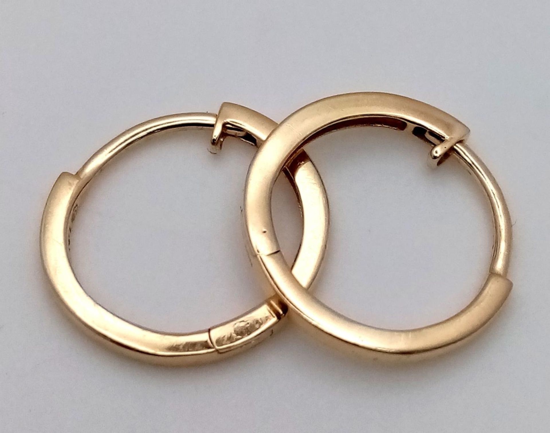 A Pair of Designer Massika 14K Yellow Gold Small Hoop Earrings. 0.8g total weight.