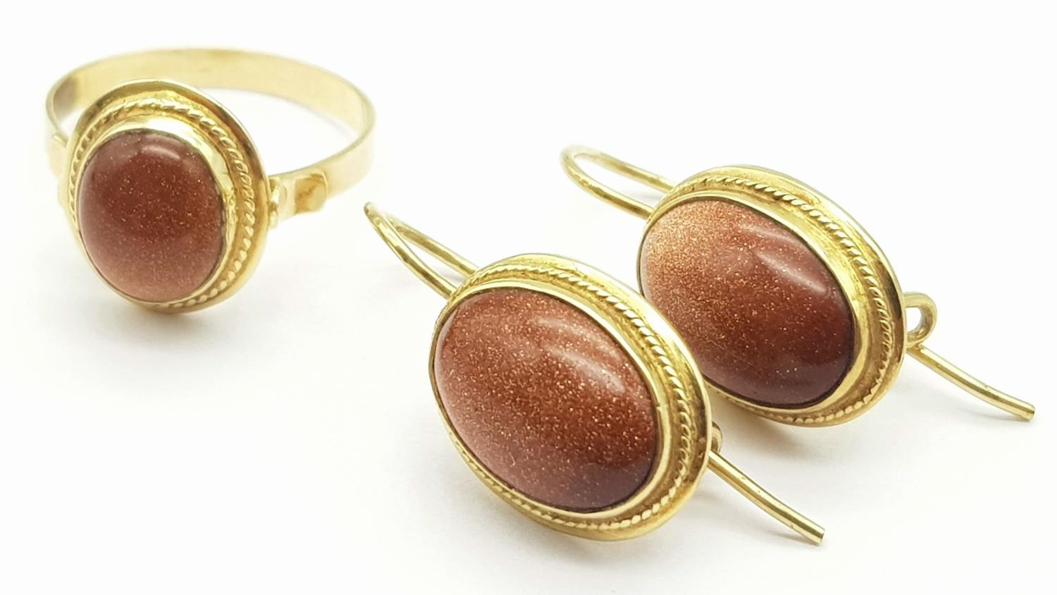 A 9 K yellow gold set of ring and earrings with "sun" stone cabochons. Ring size: P, weight: 9.2 g.