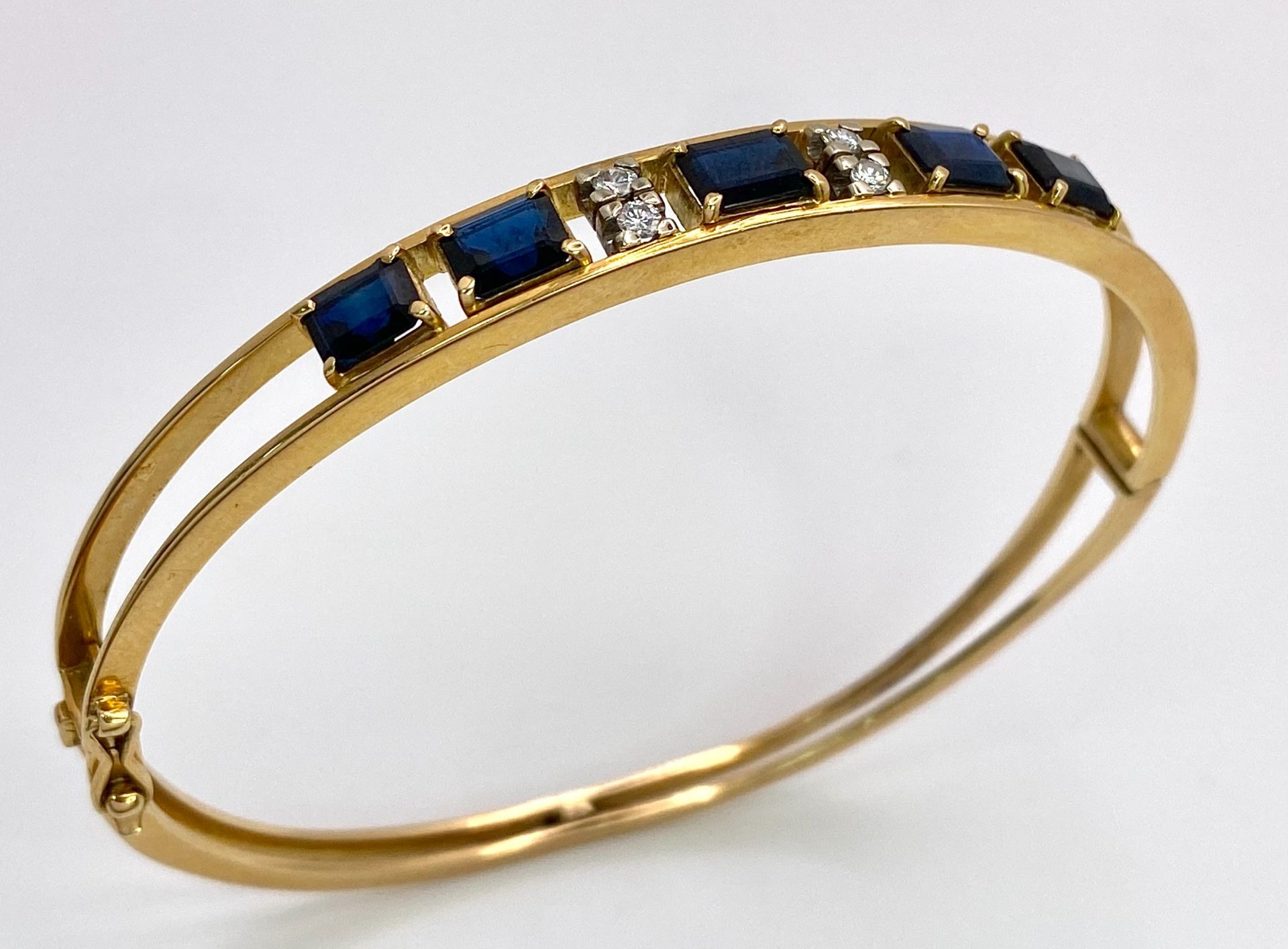 A 14K (TESTED AS) YELLOW GOLD BANGLE SET WITH 5 SAPPHIRES AND 4 DIAMONDS, 6CM DIAMETER, 15.9G (DIA: - Image 2 of 6