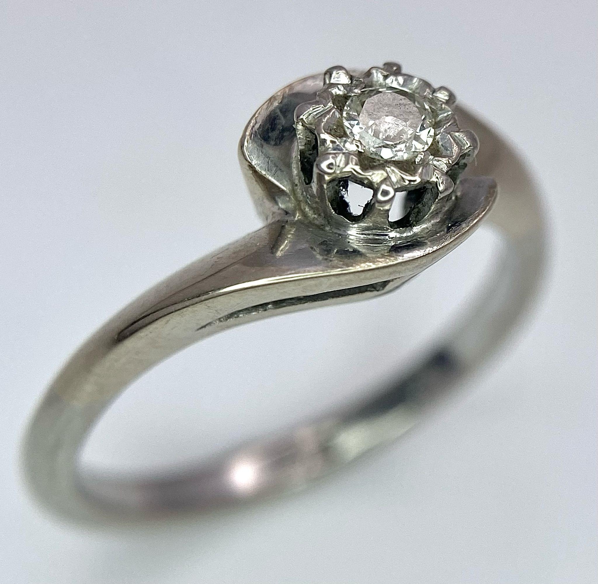 An 18K White Gold Diamond Crossover Ring. 0.10ct brilliant round cut diamond. Size N. 4g total