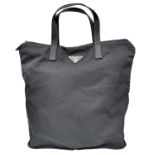 A Prada Black Compactable Tote Bag. Textile exterior with leather handles and zip top closure. Black