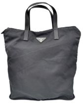 A Prada Black Compactable Tote Bag. Textile exterior with leather handles and zip top closure. Black