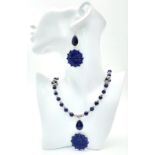 A Tibetan silver and lapis lazuli necklace and earrings set with large, carved, flower shaped discs.