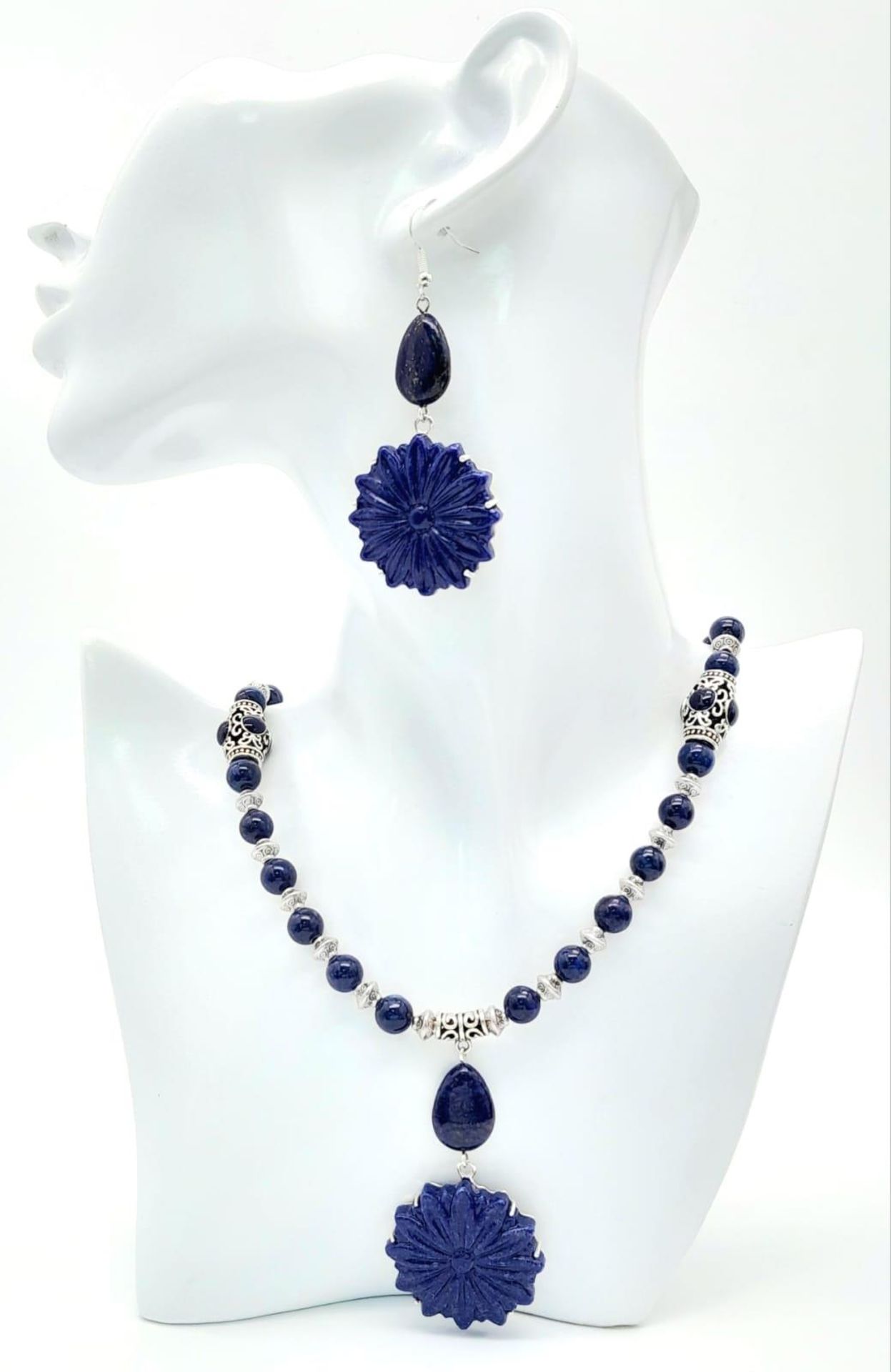 A Tibetan silver and lapis lazuli necklace and earrings set with large, carved, flower shaped discs.