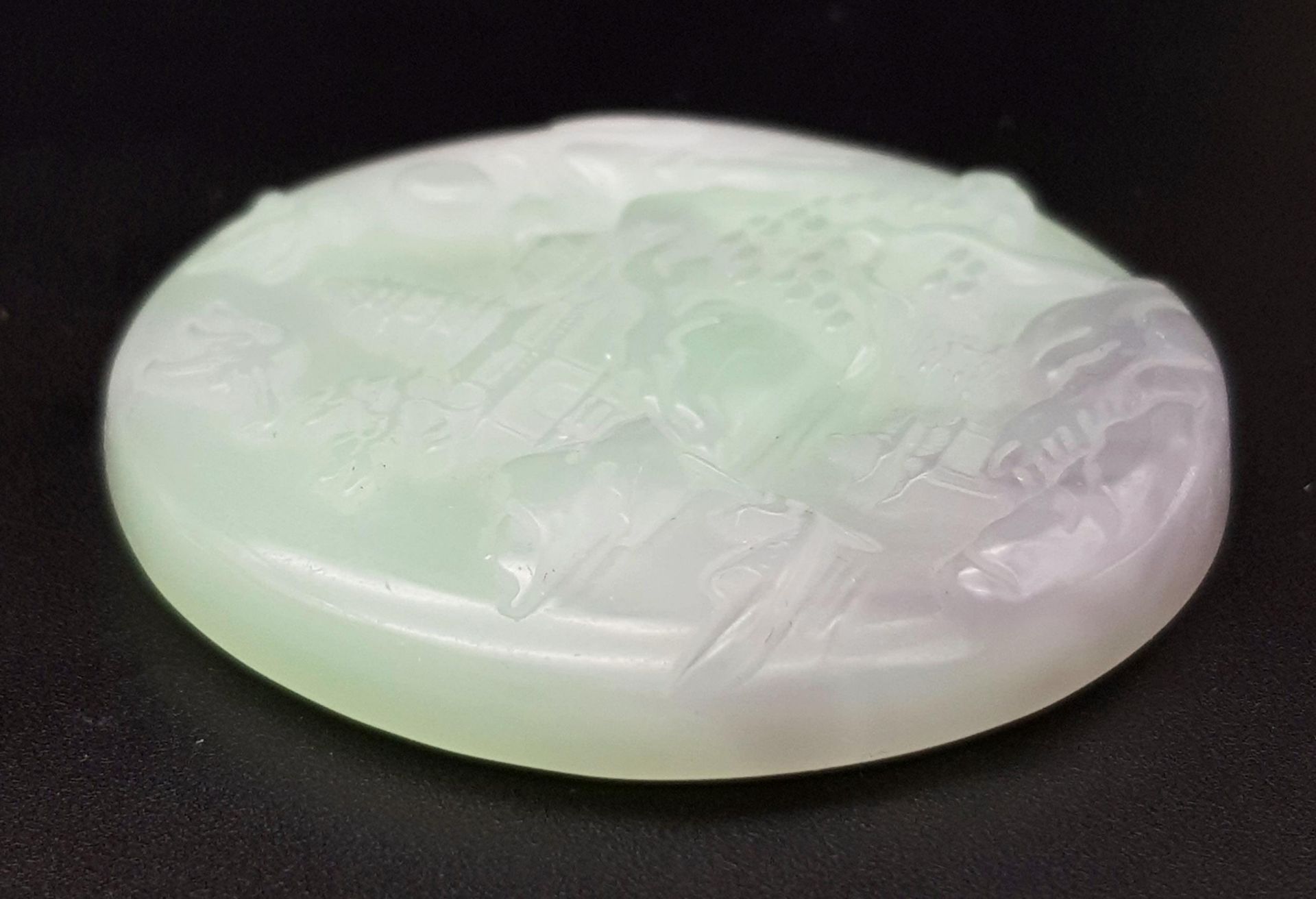 A Chinese Pale Green and White Jade Circular Pendant with Village Decoration. 5cm diameter.