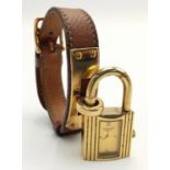 A Hermes Kelly Watch. Brown leather strap. Gold plated padlock quartz watch. Needs a battery so as