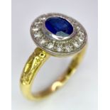 An 18 K yellow gold ring with an oval cut blue sapphire surrounded by a halo of round cut diamonds