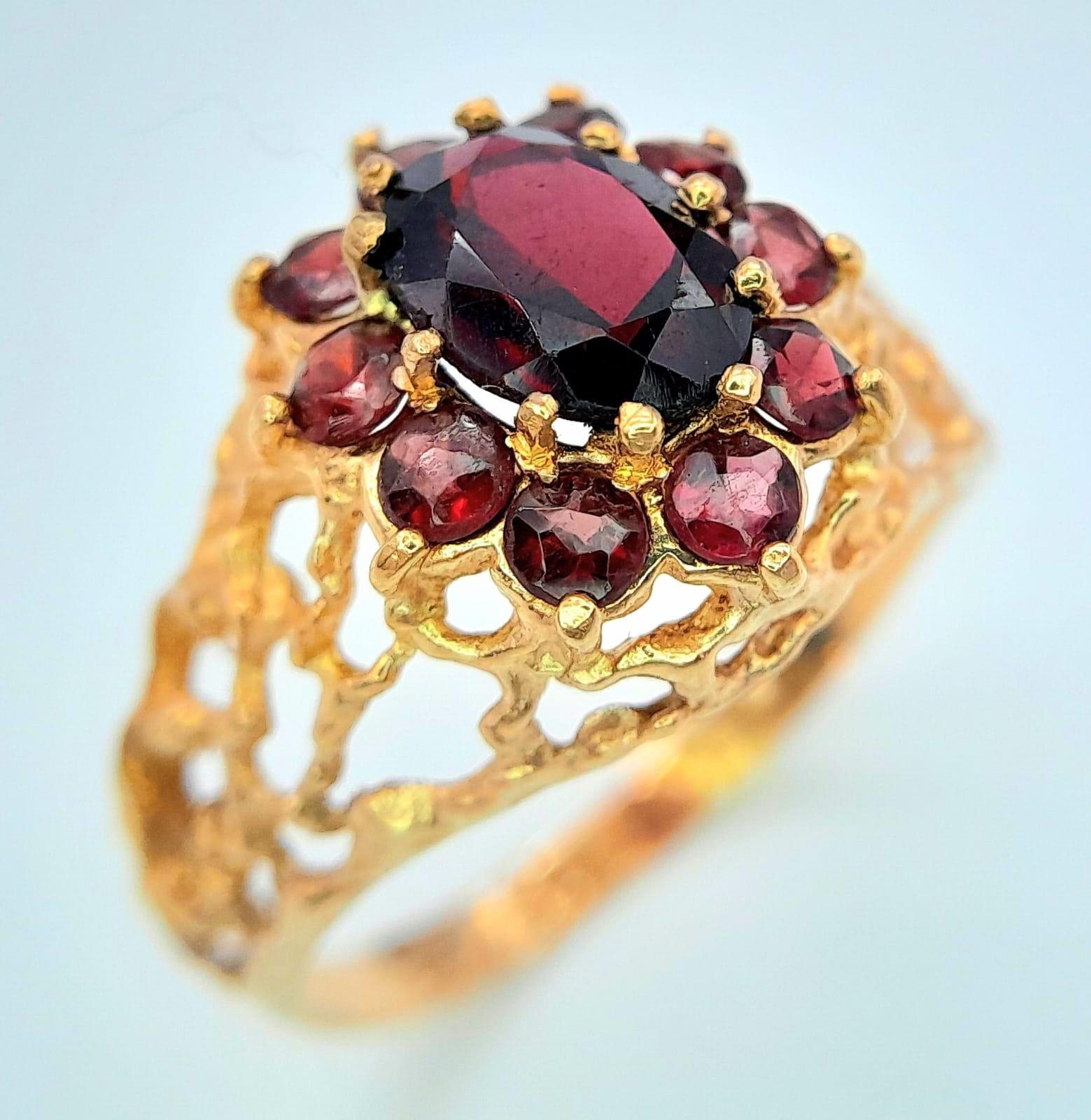A vintage oval cluster garnet 9ct gold ring surrounded by a halo of bright red garnets in a