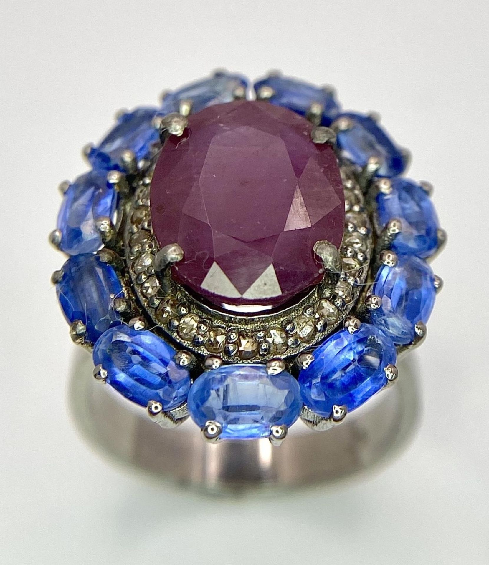A 5.65ct Ruby Dress Ring with Halo of 0.40ctw of Diamonds and 3.70ct of Kyanite Stones. Set in 925