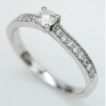 AN 18K WHITE GOLD DIAMOND SOLITAIRE RING - WITH DIAMOND SET SHOULDERS. 0.35CT. TOTAL 2.6G. SIZE N