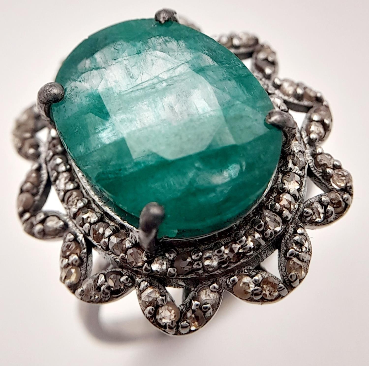 A 6.15ct Emerald Ring with 0.75ctw of Diamond Accents. Set in 925 Silver. Size N. Comes with a