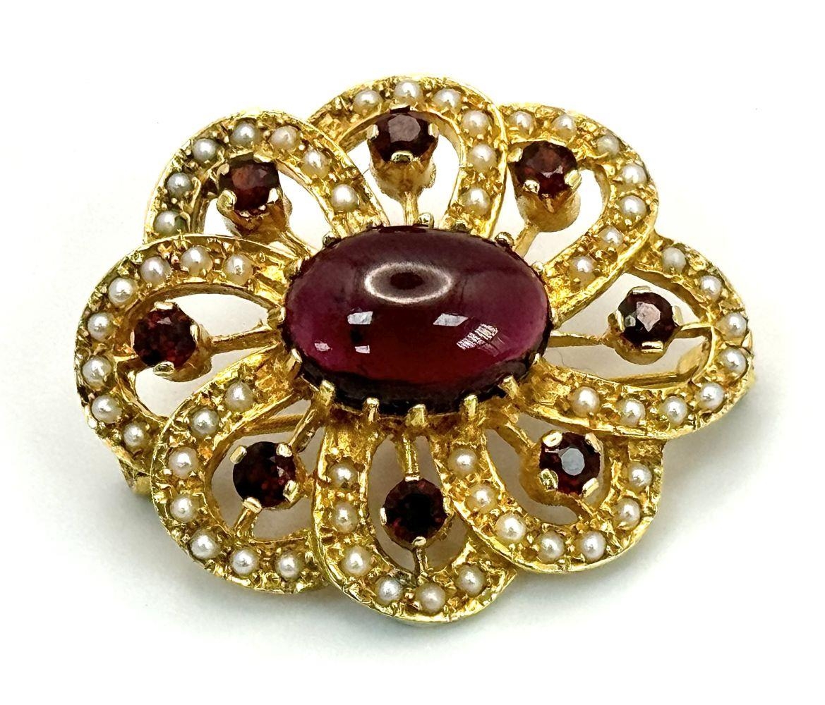 A 9K Yellow Gold Garnet and Seed Pearl Brooch. Central garnet cabochon with a decorative garnet