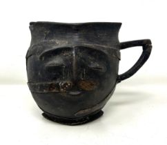 A carved wood and metal bound jug, in the form of a face, 17 cm high losses, split, see images