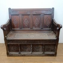 A 17th century style carved oak settle, with a painted leather panel to the seat and arms, 130 cm