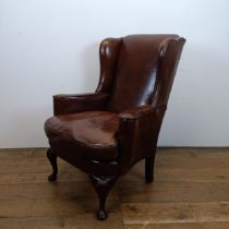 An 18th century style wing armchair, with brown leather upholstery