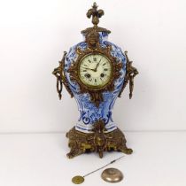 A mantel clock, the enamel dial with Roman numerals, in a Delft case with gilt metal mounts, 47 cm