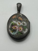 A late 19th/early 20th century, silver coloured metal and enamel oval locket, decorated flowers