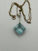 An Art Nouveau style aquamarine and seed pearl pendant, on a yellow metal chain