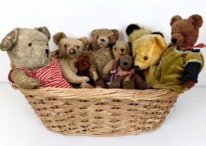 A well loved plush blond teddy bear, assorted other teddy bears and a basket