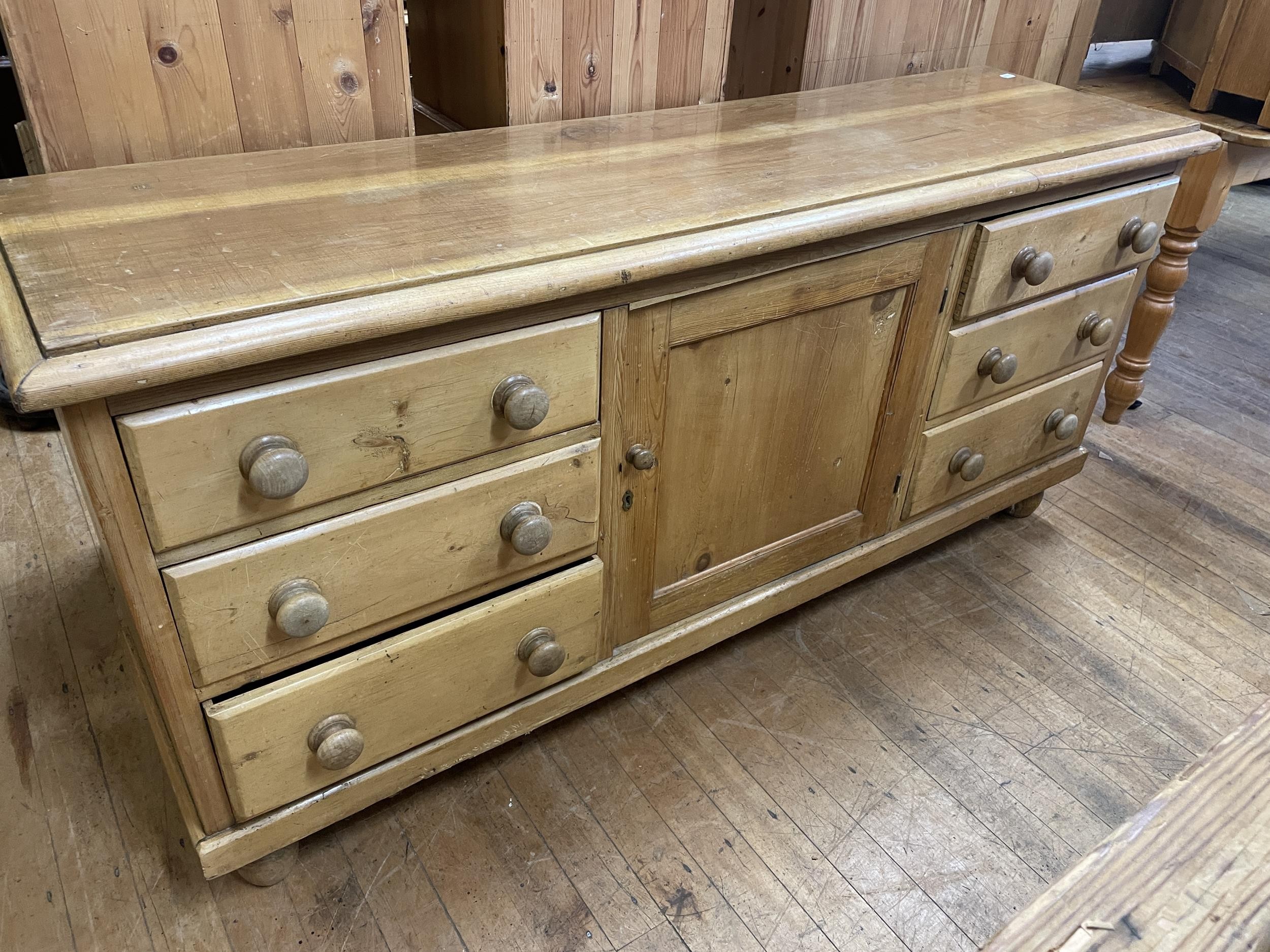 A pine dresser base, having a single cupboard door, flanked by six drawers, 88 cm wide