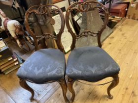 A pair of Victorian walnut balloon back chairs, with pierced top and central rails, padded seats and