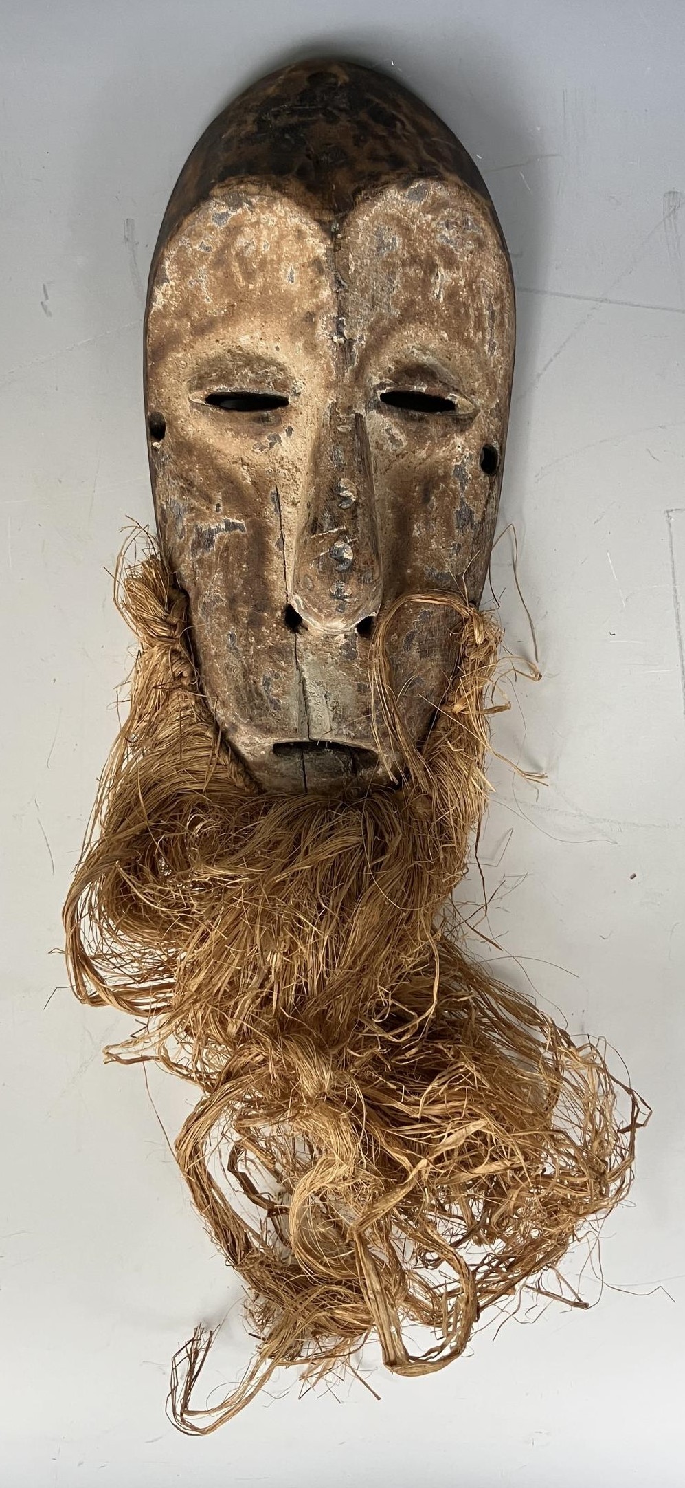 An African Lega type tribal mask, with a straw beard, 38 cm high