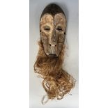 An African Lega type tribal mask, with a straw beard, 38 cm high