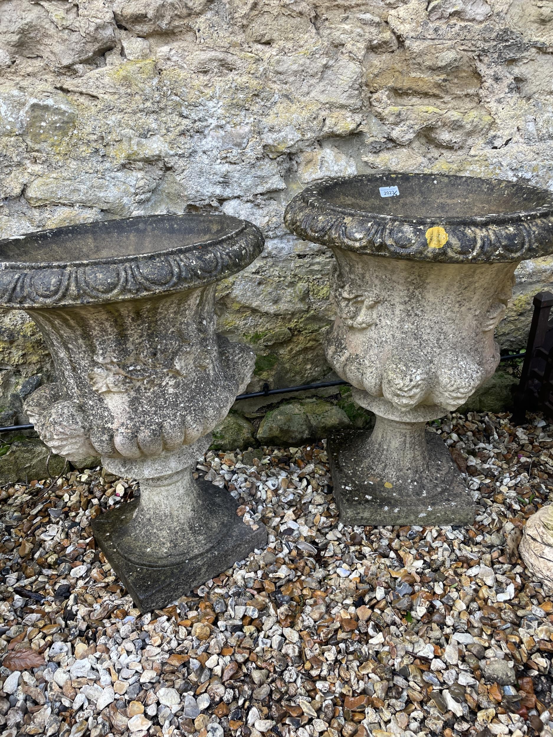 A pair of composite stone garden urns, 65 cm high