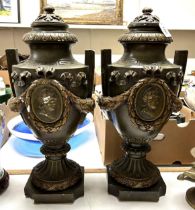 A pair of decorative painted composition urns, decorated face masks, ribbon ties and swags, slight