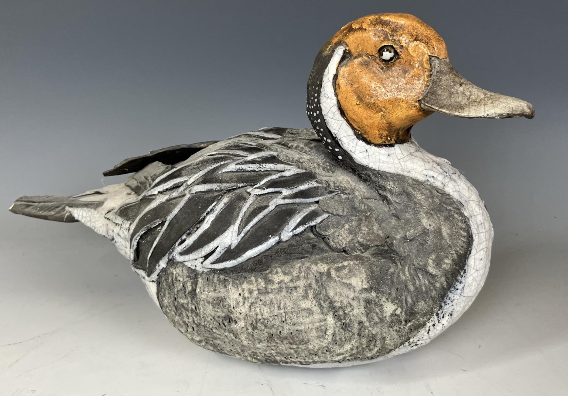 A pottery figure of a duck, 30 cm wide, and a carved and painted figure of a duck, 51 cm wide (2)