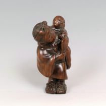 A carved wooden netsuke, in the form of mother and child, signed, 5 cm