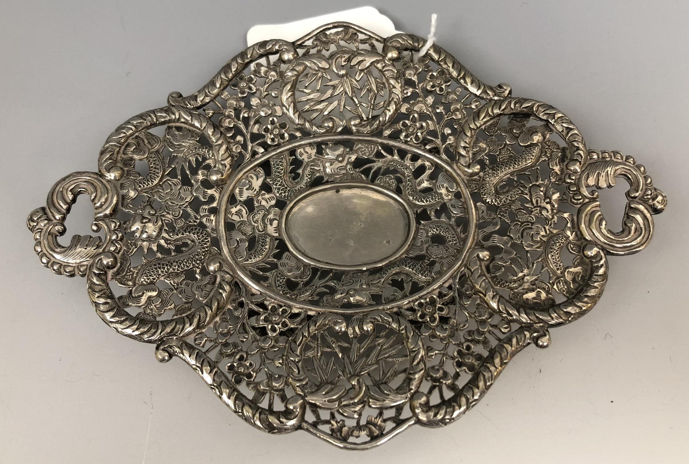 A Chinese silver coloured metal dish, embossed and pierced prunus and dragons, 15.5 cm wide 3.1 ozt