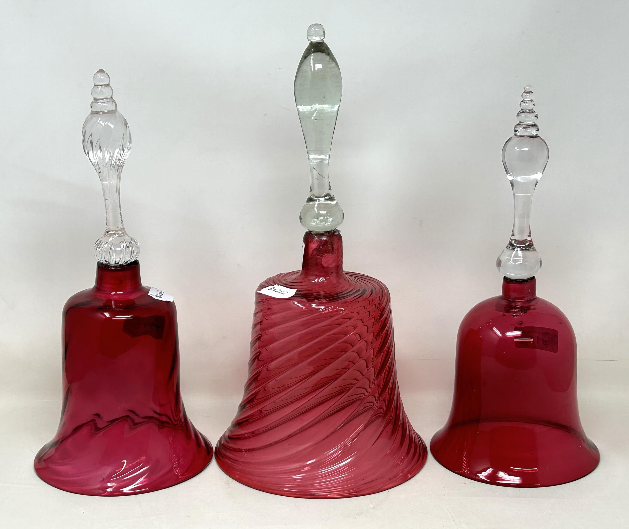 A cranberry and clear glass bell, 34 cm high, and two others, all lacking ringers (3)
