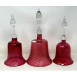 A cranberry and clear glass bell, 34 cm high, and two others, all lacking ringers (3)