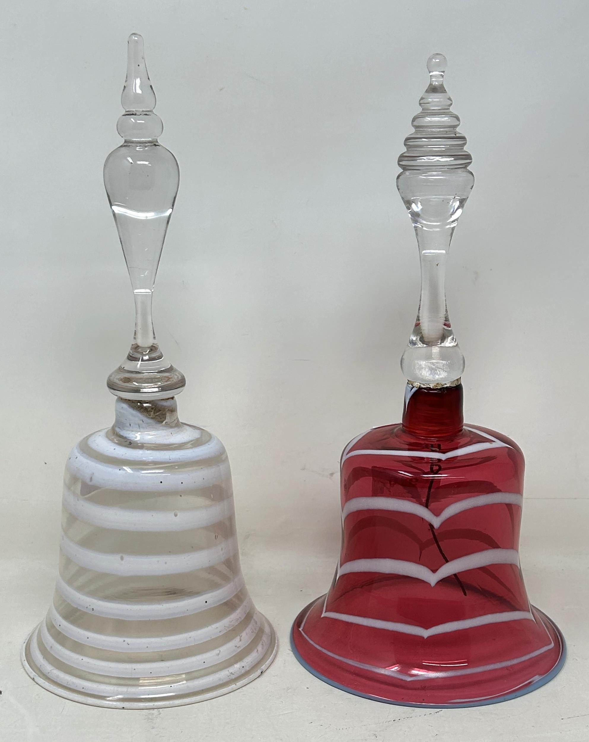 A cranberry, opaque and clear glass bell, 28 cm, and another glass bell, lacking ringers
