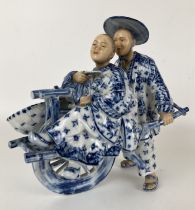 A Dutch porcelain group of an Eastern man pushing a lady in a cart, 20 cm high, and a plate (2)