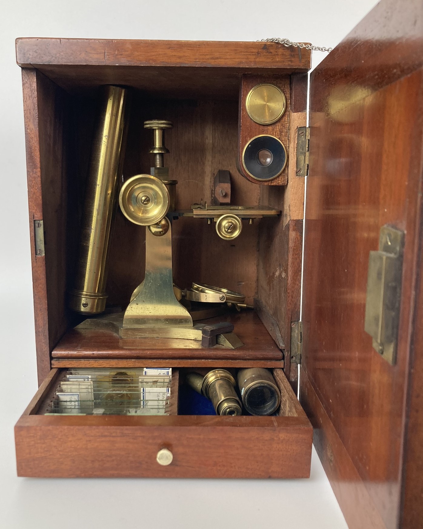A 19th century brass microscope, in a mahogany case, with a fitted drawer containing various slides