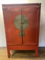 A Chinese red laquered cabinet, with metal mounts, 173 cm high x 108 cm wide