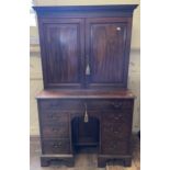 A 19th century mahogany kneehole desk, with a bookcase top having a pair of panel doors, opening